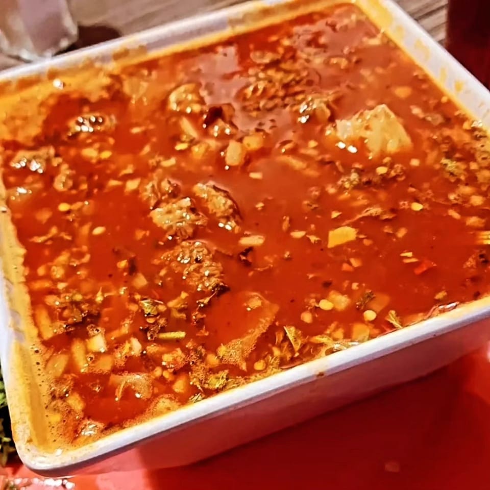 Close-up of a large white rectangular dish filled with a rich red Mexican stew.